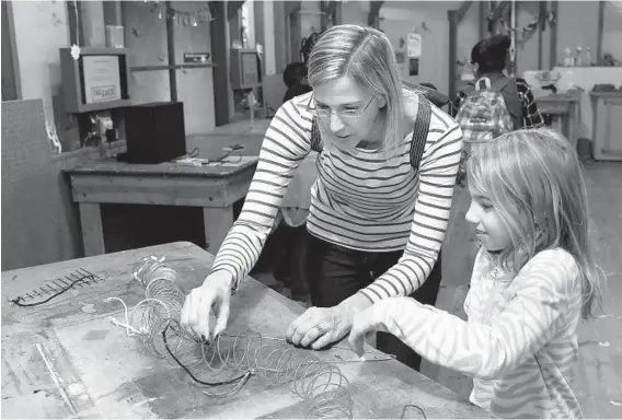  ?? BARBARA HADDOCK TAYLOR/BALTIMORE SUN PHOTOS ?? Eight-year-old Mallory McGlannan of Finksburg and her mother, Wendy McGlannan, create weird sounds using a Slinky, a coat hanger and other materials at “The Shed” exhibit at the Maryland Science Center. The center is launching a fundraisin­g initiative...