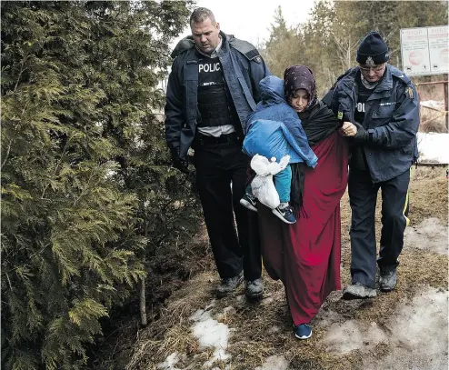  ?? DREW ANGERER / GETTY IMAGES ?? A mother and child from Turkey are escorted by RCMP after they crossed the U. S.- Canada border into Canada in Hemmingfor­d, Que. A UN agency official says most migrants appear well-prepared for their journeys.