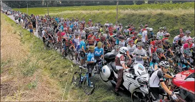  ?? AP/PETER DEJONG ?? Riders wait on the road after Tuesday’s 16th stage of the Tour de France was interrupte­d after protesting farmers blocked the road with hay bales about 18.5 miles into the 135.5-mile stage.