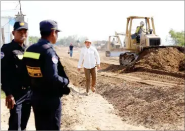  ?? SRENG MENG SRUN ?? A Chroy Changvar district resident walks through the OCIC developmen­t site earlier this year, as workers clear land to make way for the controvers­ial satellite city on the outskirts of Phnom Penh.