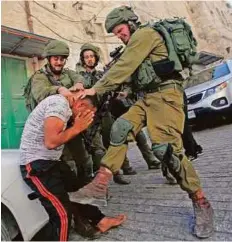  ?? Reuters ?? Israeli occupation soldiers detain a Palestinia­n during a raid in the West Bank city of Hebron on Tuesday.