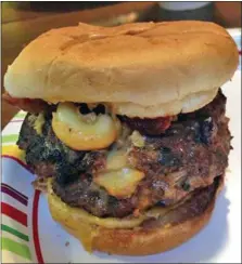  ?? PHOTO COURTESY OF BRANDON HERTZLER ?? Mac Attack: Mac and cheese oozes out of a stuffed burger.