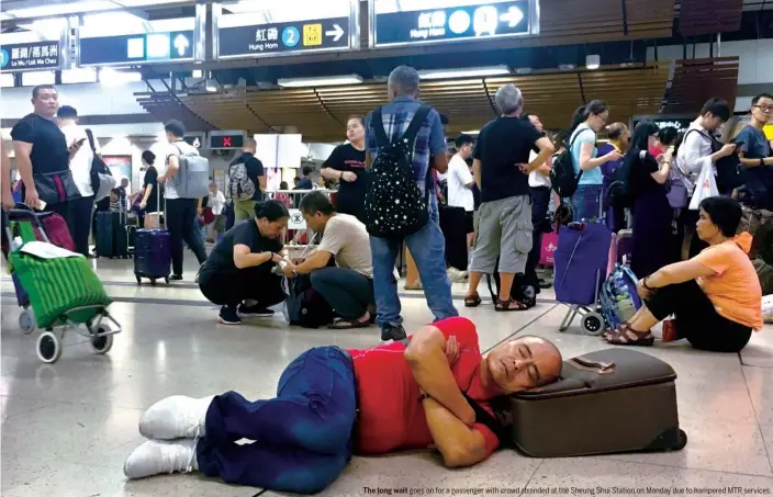  ??  ?? The long wait goes on for a passenger with crowd stranded at the Sheung Shui Station on Monday due to hampered MTR services.