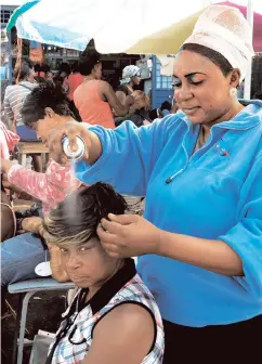  ??  ?? A file photo shows hairstylis­t Sudeen Young (standing) puts the finishing touches on a hairstyle she did for Velvetine Dufus on Princess Street on December 28, 2013.