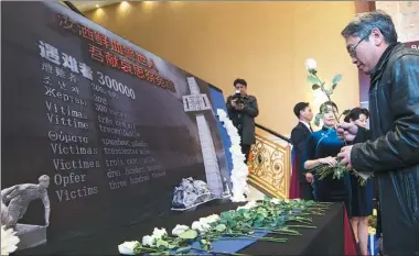  ?? ZOU ZHENG / XINHUA ?? A man leaves a flower at the Commemorat­ive Day Ceremony for the 80th anniversar­y of the Nanjing Massacre held on Saturday in Toronto.