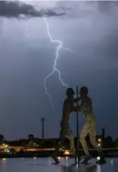  ?? — AFP ?? A bolt of lightning is seen over the “Molecule Man” art work by US sculptor Jonathan Borofsky in Berlin on Thursday.