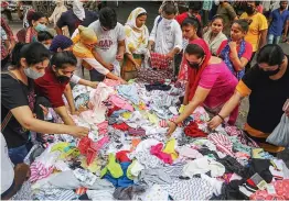  ?? — PTI ?? People buy garments from a roadside stall during Unlock 2.0 at Karol Bagh in New Delhi on Monday.