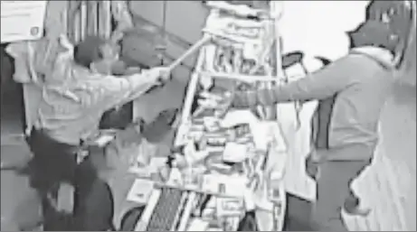  ??  ?? Store owner Luis Quizhpe uses a bat to fight off a gunman, in this image from surveillan­ce video