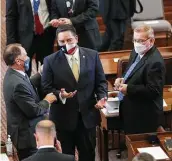  ??  ?? Rep. Philip Cortez sports a Texas flag-adorned face mask while chatting with other state legislator­s before the session was convened.