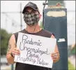  ?? Associated Press ?? Sean Harris holds a sign asking for help in New Orleans on Friday. Harris had just completed training to be a hunted history tour guide in the French Quarter when the coronaviru­s pandemic hit. He has not been able to find a job since.