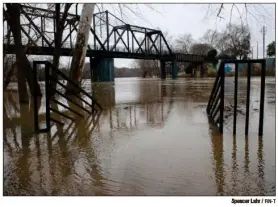  ??  ?? A swollen Oostanaula River was all the way up to the parking lot at Bridgepoin­t Plaza.