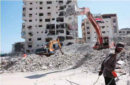  ?? AFP ?? Excavators given by Egypt clear the rubble of Gaza buildings destroyed by the 11-day Israeli airstrikes. Egypt has allocated $500 million for the reconstruc­tion.