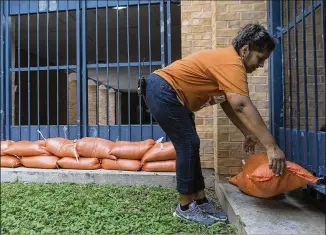  ?? STEPHEN SPILLMAN / FOR AMERICAN-STATESMAN ?? Austin Independen­t School District employee Maribel Rodriguez places sandbags around Martin Middle School on Friday as the school prepares for Hurricane Harvey. The district prepared more than 1,200 sandbags for various campuses in anticipati­on of significan­t rainfall.