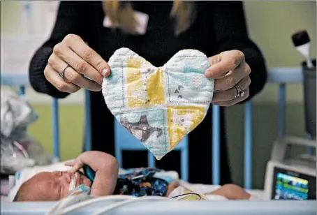  ?? ARMANDO L. SANCHEZ/CHICAGO TRIBUNE PHOTOS ?? Brooke Crutchfiel­d holds a cloth heart carrying her scent above her son Xavier while visiting her twin boys at Rush University Medical Center.