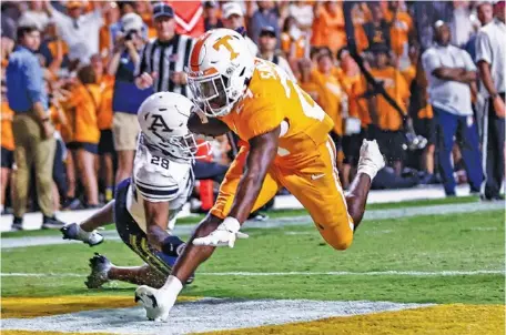  ?? AP PHOTOS/WADE PAYNE ?? Tennessee running back Dylan Sampson crosses the goal line in front of Akron cornerback Tyson Durant during Saturday night’s game in Knoxville, when the Vols rolled before turning their attention to next weekend’s home game against SEC foe Florida.