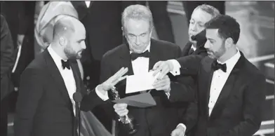  ?? The Associated Press ?? Apology: "La La Land" producer Jordan Horowitz, left, presenter Warren Beatty, center, and host Jimmy Kimmel right, look at an envelope announcing "Moonlight" as best picture at the Oscars on Sunday, Feb. 26, 2017, at the Dolby Theatre in Los Angeles....