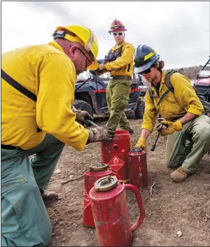  ?? ?? Josh Cornell (from left) and Justin Short with Forestry, Fire and State Lands assist Heston Burr as he refills drip torches to start a prescribed burn.