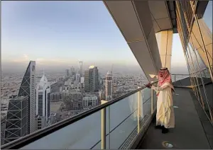  ?? Bloomberg News/SIMON DAWSON ?? An employee looks out from the 32nd-floor viewing platform of the Al Faisaliah Tower in Riyadh, Saudi Arabia, in December. The government-owned national oil company Aramco is trying to reform and diversify its oil-dependent economy.