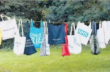  ?? SUZIE HOWELL/THE NEW YORK TIMES ?? Cotton totes accumulate­d by a single person hang on a laundry line in London.