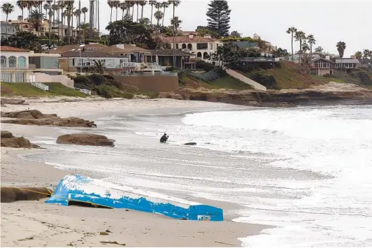  ?? JOHN GIBBINS U-T FILE ?? A overturned Mexican fishing panga on the beach at Windansea in La Jolla in May 2018 remains after the 10 people it carried from Mexico were arrested by federal authoritie­s. After the boat came ashore, nine men and one woman were taken into custody.