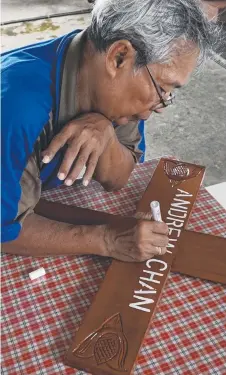  ??  ?? GRIM TASK: A mortician has inscribed the names of the execution victims and April 29 date of their deaths on crosses.