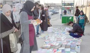  ?? — AFP ?? Iraqis buy and sell books on a pavement in the former embattled city of Mosul.