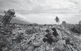  ?? Mohd Rasfan, Getty Images ?? Residents sit among debris at the Perumnas Balaroa village in Palu in Indonesia’s central Sulawesi region Saturday, following the Sept. 28 earthquake and tsunami.