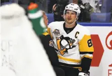  ?? Kevin Hoffman / Getty Images ?? A trainer treats Sidney Crosby after he lost two teeth to a high stick by Buffalo’s Evander Kane in the third period.