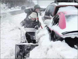  ??  ?? The Associated Press Alfonso Velez, front, and his son Mark Velez, 15, plow around vehicles Sunday after Saturday’s blizzard in Minneapoli­s.