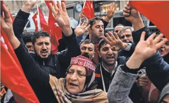  ?? YASIN AKGUL, AFP/ GETTY IMAGES ?? Protesters wave flags and give a four- fingered salute that symbolizes solidarity with the Muslim Brotherhoo­d during a protest in front of the Dutch consulate on Sunday in Istanbul.