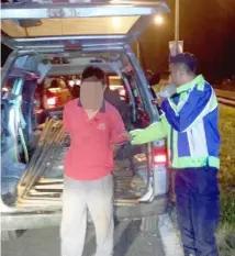  ??  ?? A police patroller takes custody of the suspect at Mile 16 of Kuching-Serian Road.