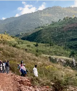  ?? ?? À gauche, en bas, puis dans le sens horaire : Gérald Fortiné avec un billet obtenu à un poste de péage ; la mer, vue du haut du sentier ; des hommes, des femmes et des enfants passent par ce chemin contrôlé.