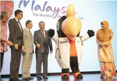  ?? MHTC FOR JAWA POS ?? SIAP SAMBUT 2020: Sherene Azli (kanan) dan Wakil Menteri Keuangan Malaysia Amiruddin bin Haji Hamzah mengapit maskot wisata medis Visit Malaysia 2020.