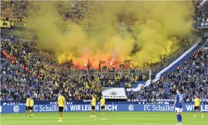  ??  ?? Dortmund fans burn flares and let off yellow smokebombs in the last Revierderb­y played in front of fans in October 2019. Photograph: Martin Meissner/AP