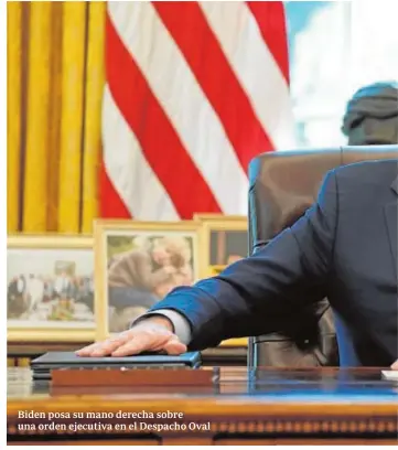  ??  ?? Biden posa su mano derecha sobre una orden ejecutiva en el Despacho Oval