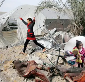  ??  ?? فتاة فلسطينية تتفقد منزال دمرته إسرائيل في رفح أمس، وفي اإلطار طفلة تحمل لعبتها في منزلها المدمر. (أ.ف.ب)