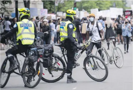  ??  ?? Montreal police keep an eye on demontrato­rs calling for justice in the death of George Floyd and all victims of police brutality, A Toronto city councillor suggests it’s problemati­c to expect police officers to act as social workers.