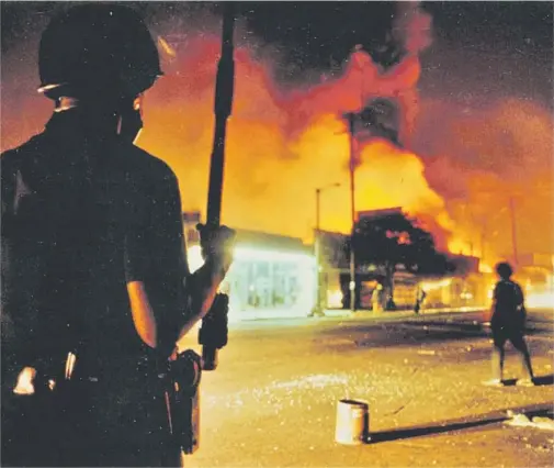  ?? Gary Friedman Los Angeles Times ?? LAPD officer watches buildings burning unabated at Central and 46th Street during violence that exploded across the city in April 1992.