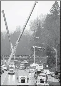  ?? AP/ELAINE THOMPSON ?? A crane lowers
a damaged Amtrak train car from an overpass Tuesday at the scene of Monday’s deadly derailment over Interstate 5 in DuPont, Wash.