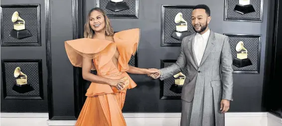  ?? Jordan Strauss / Associated Press ?? John Legend had a twist on a classic with an Alexander McQueen suit with a half-short, half-long jacket, while wife Chrissy Teigen wore a Yanina Couture gown.