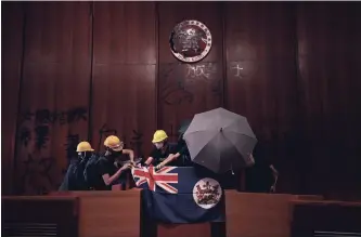  ?? VINCENT YU ASSOCIATED PRESS FILE PHOTO ?? Protesters drape a Hong Kong colonial flag on a podium in the legislativ­e chamber after breaking into the Legislativ­e Council building in Hong Kong on July 1.