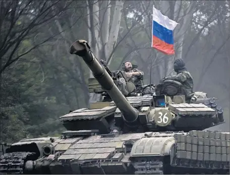  ?? VADIM GHIRDA/AP 2014 ?? A pro-Russian rebel,
left, rides on a tank flying
Russia’s flag near Donetsk in eastern Ukraine. At least 6,000 people have been killed on both sides.