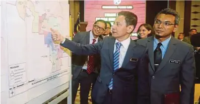  ?? [FOTO MOHD FADLI HAMZAH /BH] ?? Azhar Azizan bersama Mohd Nizam melihat peta kawasan pada sidang media PRK DUN Rantau, di Putrajaya.