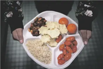  ?? WONG MAYE-E/AP ?? INSTEAD OF SATURDAY, FEB. 11 – A SEVENTH GRADER carries her plate which consists of three bean chili, rice, mandarins and cherry tomatoes and baked chips during her lunch break at a local public school on Friday in the Brooklyn borough of New York. A 2010 federal law that boosted nutrition standards for school meals may have helped curb obesity among America’s children _ even teenagers who can buy their own snacks, according to a study published Mondayin the journal JAMA Pediatrics.