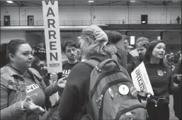  ?? TRIBUNE NEWS SERVICE ?? Supporters for presidenti­al candidates Sen. Bernie Sanders and Sen. Elizabeth Warren attempt to persuade an Andrew Yang supporter, center, into their respective groups during a realignmen­t round of a satellite caucus Monday at the Drake University field house in Des Moines, Iowa.