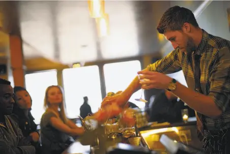  ?? Photos by Carlos Avila Gonzalez / The Chronicle ?? Ian Anderson pours drinks at 15 Romolo. The “glove law” requires him to wear and change gloves when he adds garnishes.