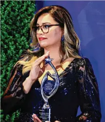  ?? Bill Glass Photograph­y/Contribute­d photo ?? Emanuela Palmares, vice president of The New American Dream Foundation, holds a scholarshi­p awards statuette during the foundation’s annual gala, which was held at the Amber Room Colonnade on Sept. 15.