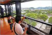  ?? KATSUMI TANAKA / THE YOMIURI SHIMBUN ?? People look out from the donjon (tower) of Kumamoto Castle. The castle was severely damaged by the Kumamoto earthquake in 2016 and was rebuilt.