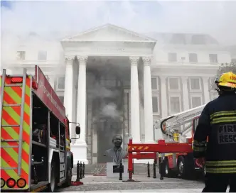  ?? (Elmond Jiyane/GCIS/Reuters) ?? A FIREFIGHTE­R looks at the smoke rising after a fire broke out yesterday in the Parliament in Cape Town.