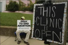  ?? ROGELIO V. SOLIS — THE ASSOCIATED PRESS ?? An anti-abortion supporter sits behind a sign that advises the Jackson Women's Health Organizati­on clinic is still open in Jackson, Miss., July 6, 2022.